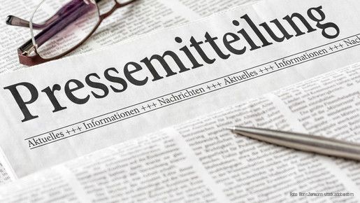 Zeitung mit der Überschrift Pressemitteilung mit brille und kuli