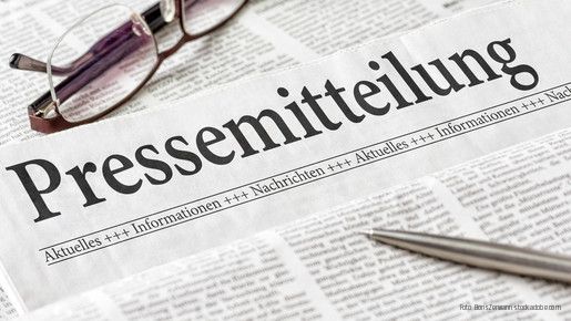 Zeitung mit der Überschrift Pressemitteilung mit Brille und Kuli