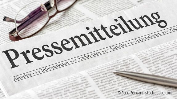 Zeitung mit der Überschrift Pressemitteilung mit Brille und Kuli